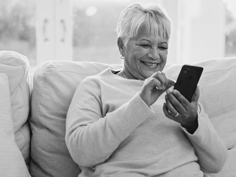 Smiling Woman Sitting on Couch Looking at Phone