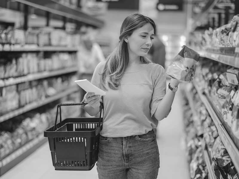 Woman Walking Grocery Aisle Looking at Food Package